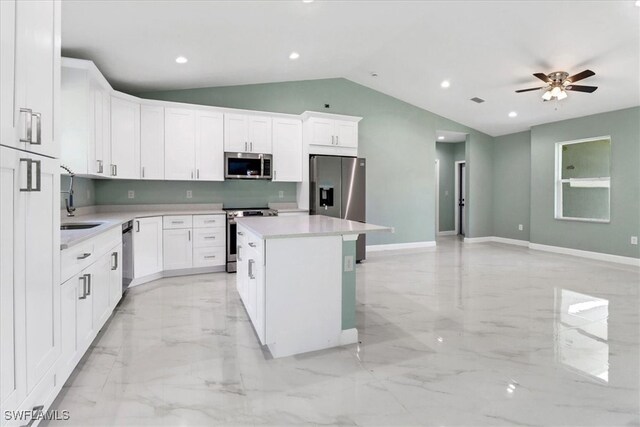 kitchen featuring lofted ceiling, sink, a center island, stainless steel appliances, and white cabinets