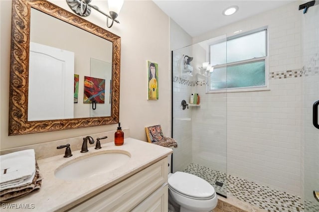 bathroom featuring vanity, a shower with shower door, and toilet