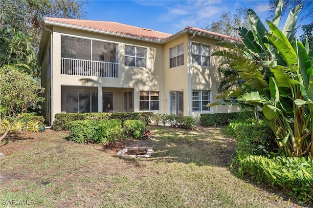 rear view of property featuring an outdoor fire pit and a lawn