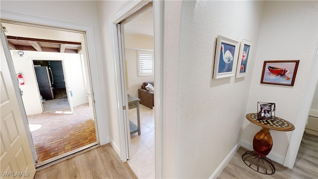 corridor with beam ceiling and light hardwood / wood-style floors