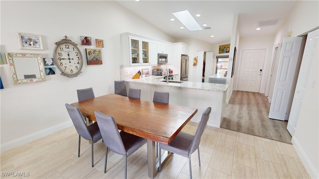 dining room with sink and lofted ceiling with skylight