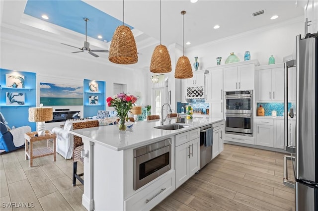 kitchen featuring stainless steel appliances, sink, a center island with sink, and white cabinets