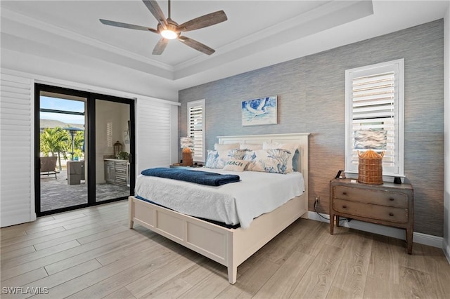 bedroom featuring crown molding, a raised ceiling, light hardwood / wood-style flooring, and access to outside