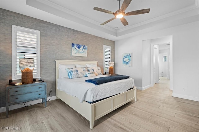 bedroom with a tray ceiling, ornamental molding, ceiling fan, and light wood-type flooring