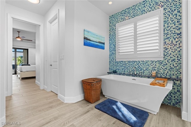 bathroom with hardwood / wood-style floors, a bathing tub, and ceiling fan