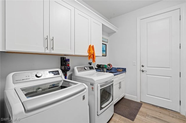 laundry room with cabinets, sink, washer and dryer, and light hardwood / wood-style flooring