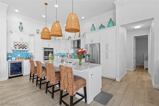 kitchen with wine cooler, white cabinetry, an island with sink, and appliances with stainless steel finishes