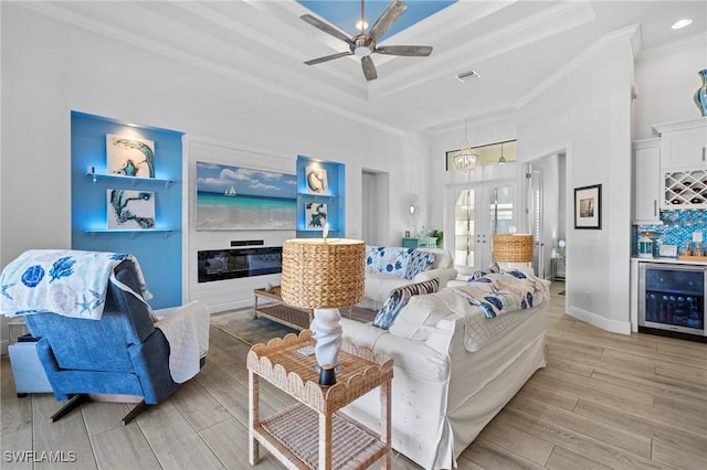 living room with wine cooler, bar area, crown molding, and light wood-type flooring