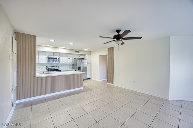 kitchen featuring white cabinets, decorative backsplash, ceiling fan, kitchen peninsula, and stainless steel appliances