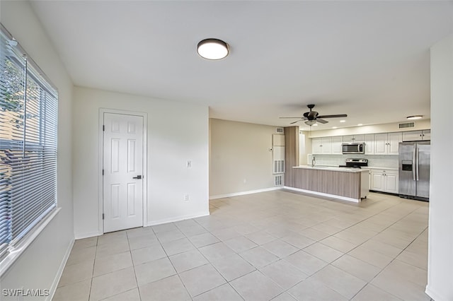 unfurnished living room with sink, light tile patterned floors, and ceiling fan