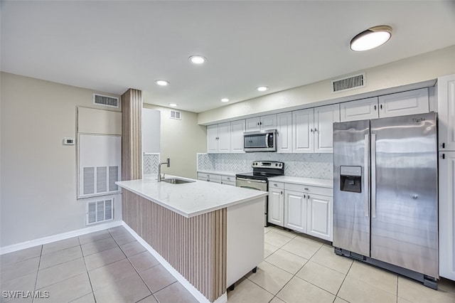 kitchen featuring light tile patterned flooring, sink, appliances with stainless steel finishes, decorative backsplash, and white cabinets