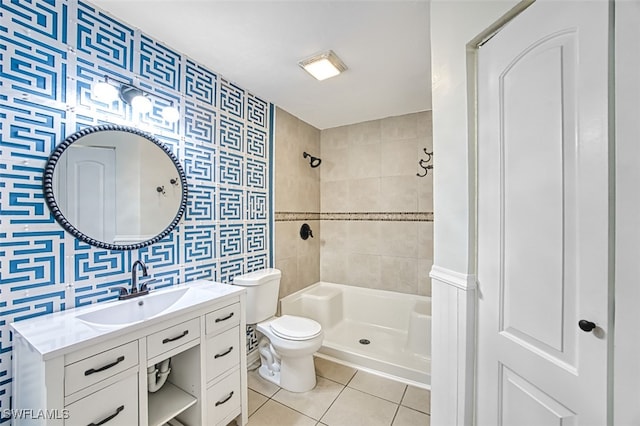 bathroom with tile walls, tile patterned flooring, vanity, tiled shower, and toilet