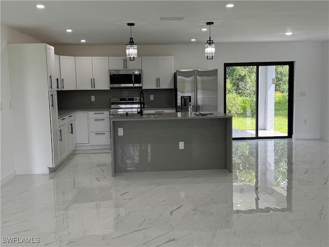 kitchen featuring hanging light fixtures, appliances with stainless steel finishes, a kitchen island with sink, and white cabinets