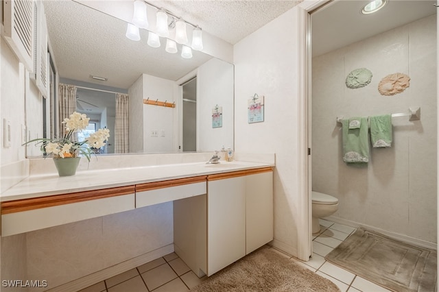 bathroom with tile patterned flooring, vanity, a textured ceiling, and toilet