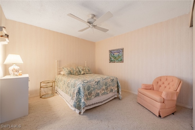 carpeted bedroom featuring ceiling fan and a textured ceiling