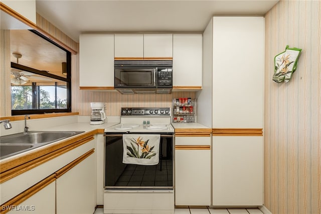 kitchen featuring electric range oven, sink, and white cabinets