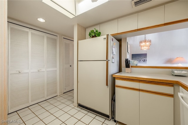 kitchen with decorative light fixtures, white cabinetry, light tile patterned floors, a notable chandelier, and white appliances