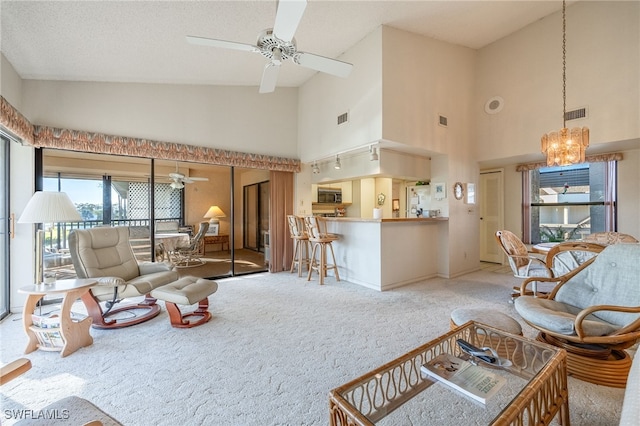 living room with carpet, ceiling fan with notable chandelier, and high vaulted ceiling