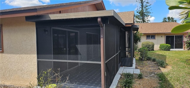 view of side of home featuring a sunroom and a lawn