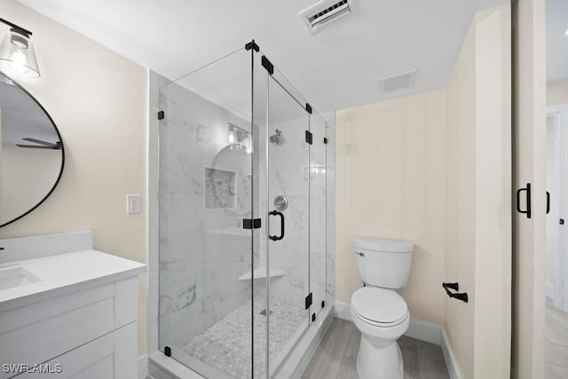 bathroom with vanity, hardwood / wood-style flooring, a shower with door, and toilet