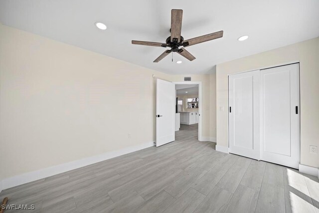 unfurnished bedroom featuring ceiling fan, a closet, and light hardwood / wood-style flooring