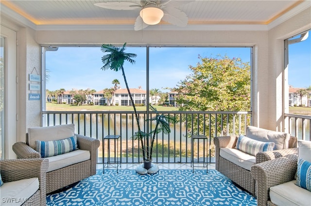 sunroom with ceiling fan, a water view, and a residential view