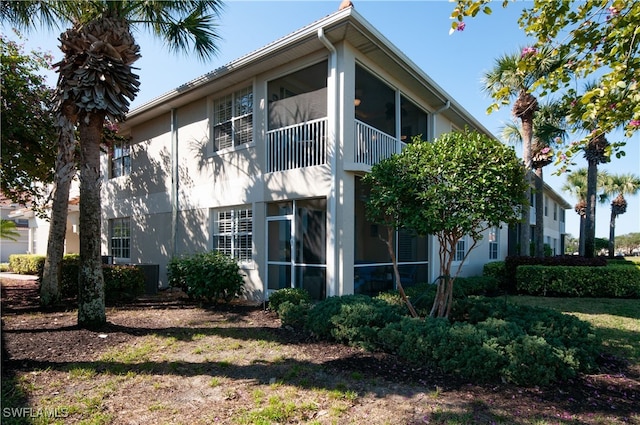 view of home's exterior with a sunroom and stucco siding