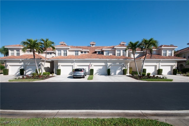 view of front of home featuring driveway, a tile roof, a residential view, and a garage