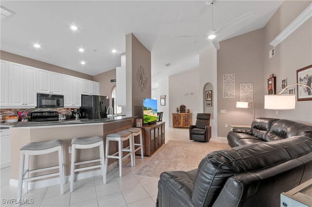 living area featuring arched walkways, visible vents, lofted ceiling, and light tile patterned floors