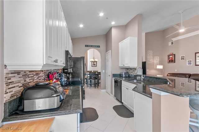 kitchen featuring arched walkways, white cabinets, dishwasher, a kitchen breakfast bar, and a peninsula