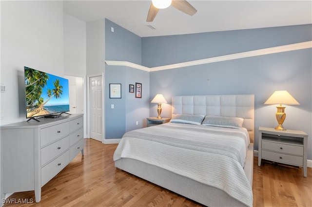 bedroom featuring light wood finished floors, visible vents, baseboards, ceiling fan, and vaulted ceiling