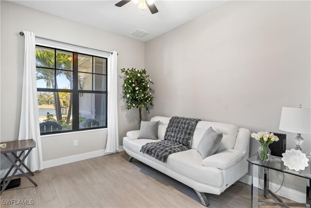 living area featuring visible vents, light wood-style flooring, baseboards, and a ceiling fan