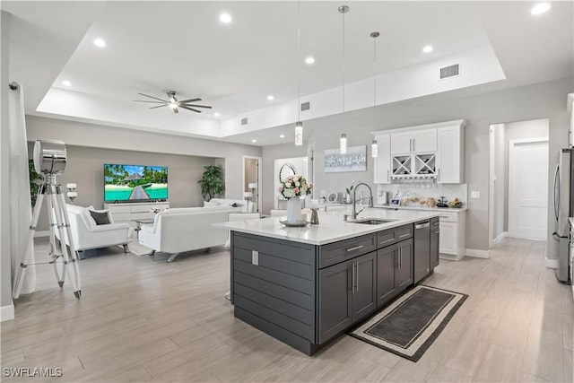 kitchen featuring a sink, light countertops, white cabinetry, a raised ceiling, and open floor plan