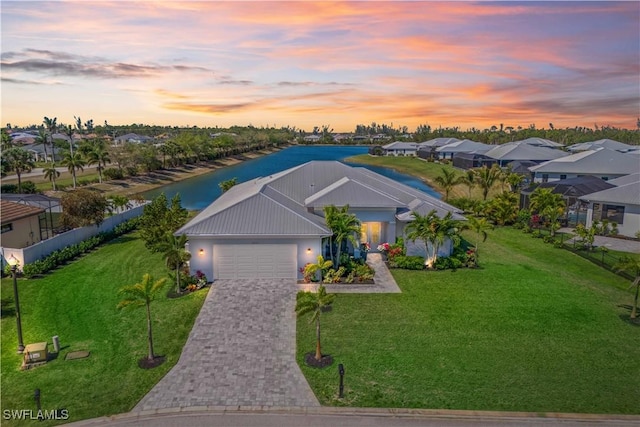 aerial view at dusk with a water view and a residential view