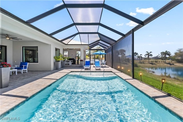 pool featuring a patio area, glass enclosure, ceiling fan, and a water view