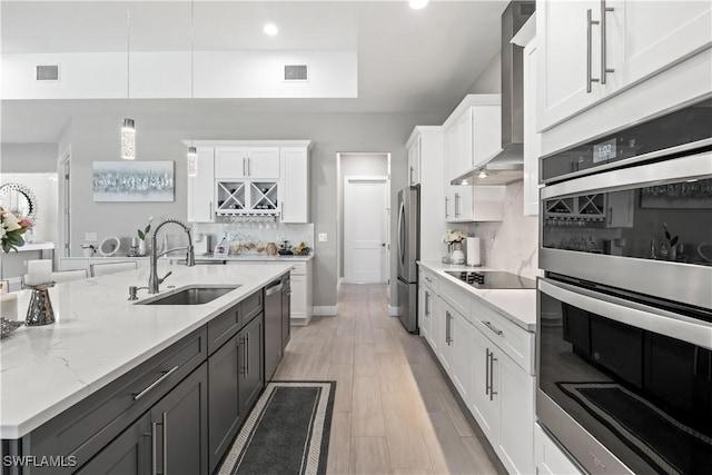 kitchen with visible vents, appliances with stainless steel finishes, white cabinetry, wall chimney exhaust hood, and a sink