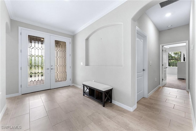 foyer entrance with ornamental molding and french doors