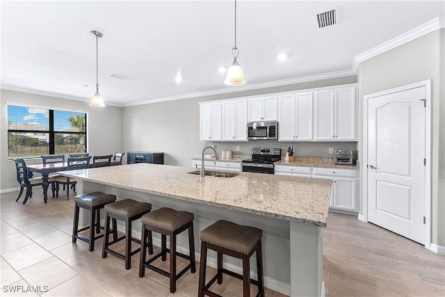 kitchen featuring appliances with stainless steel finishes, a center island with sink, white cabinets, pendant lighting, and sink