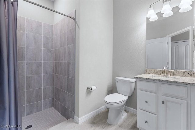 bathroom with a tile shower, vanity, and toilet