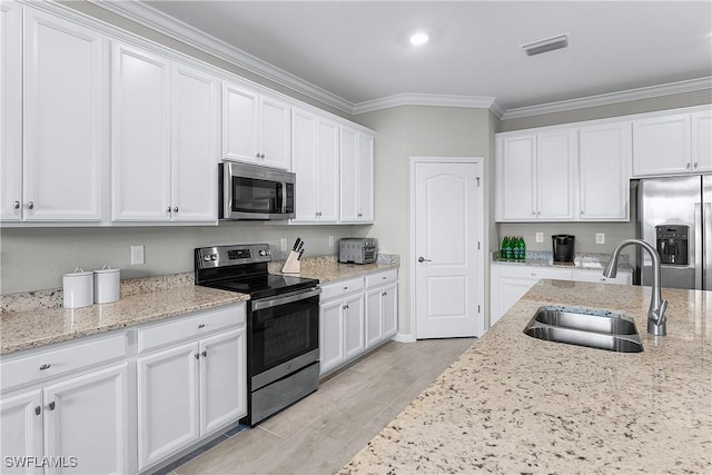 kitchen featuring stainless steel appliances, light stone counters, crown molding, sink, and white cabinetry