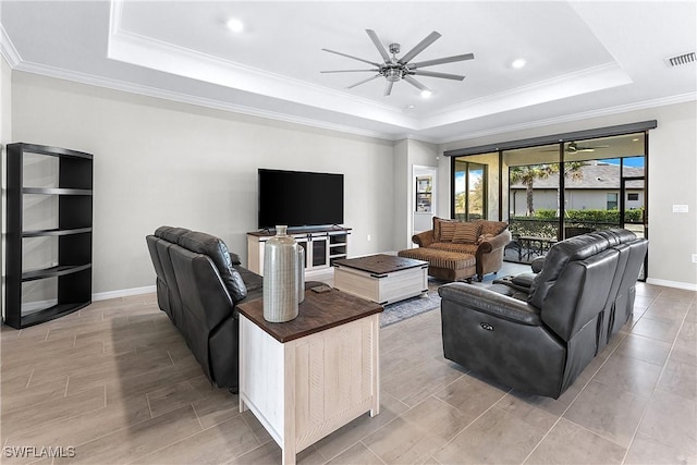 living room with ornamental molding, ceiling fan, and a raised ceiling