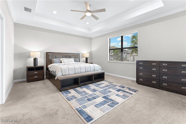 carpeted bedroom with ceiling fan, a tray ceiling, and ornamental molding