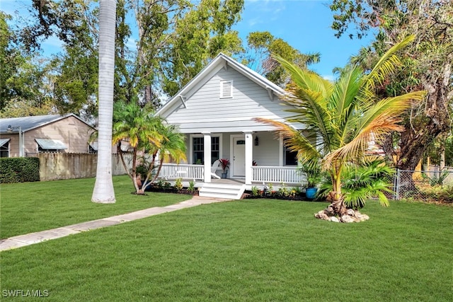 view of front of home featuring a front yard, covered porch, and fence