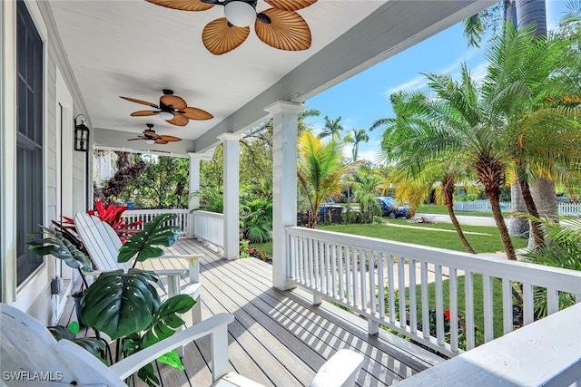 wooden deck featuring ceiling fan, covered porch, and a yard