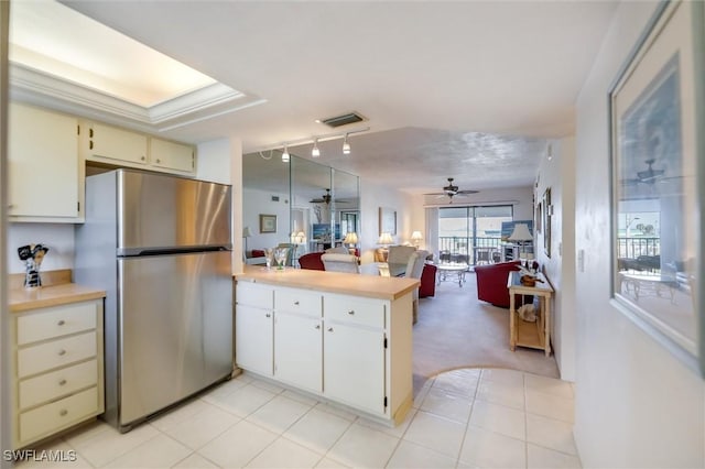 kitchen featuring ceiling fan, light tile patterned floors, stainless steel refrigerator, and kitchen peninsula