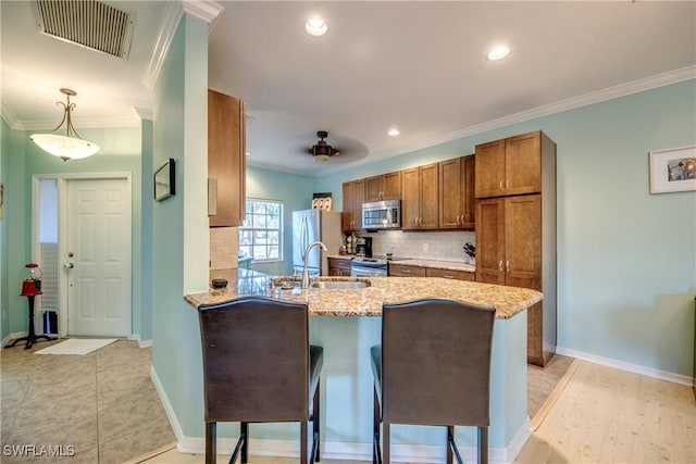 kitchen featuring a kitchen bar, sink, hanging light fixtures, kitchen peninsula, and stainless steel appliances