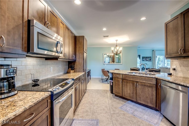 kitchen with appliances with stainless steel finishes, sink, hanging light fixtures, ornamental molding, and light tile patterned floors