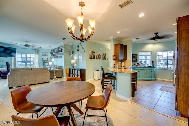 dining area featuring ceiling fan with notable chandelier, ornamental molding, a healthy amount of sunlight, and sink