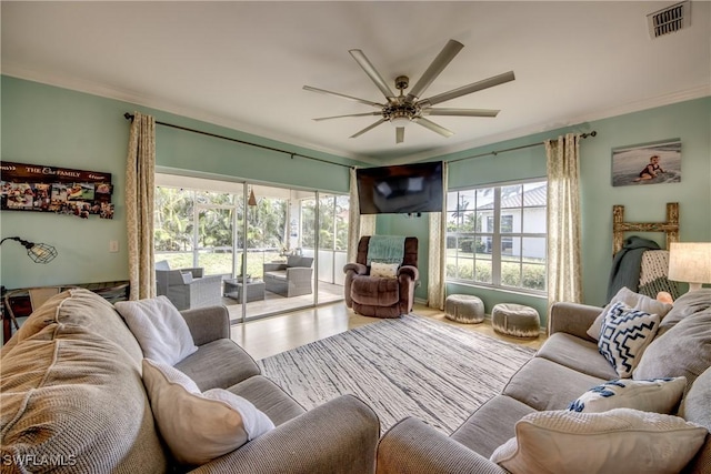 living room featuring ceiling fan, ornamental molding, a healthy amount of sunlight, and wood-type flooring