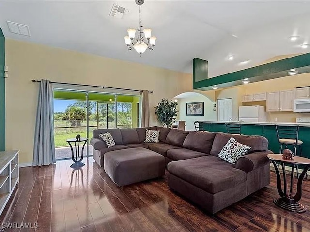 living room featuring dark hardwood / wood-style flooring, vaulted ceiling, and a notable chandelier